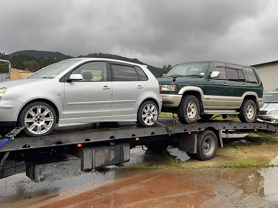 Tow truck transporting three scrap cars for removal in whanganui